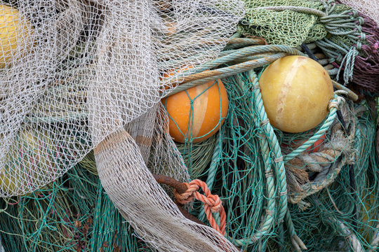 Old green and grey fishernet and other fishermens equipment, yellow and orange lifting bowls