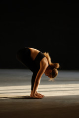 Young woman practicing yoga, doing head to knees, uttanasana exercise, Standing forward bend pose.