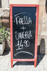 Blackboard of a restaurant in Barcelona, Spain, offering two typical Spanish products: paella and sangria