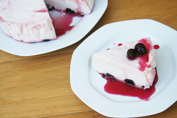 Cheesecake with sour cherries and sauce on a plate on wooden table. Sour cherry cheesecake on a plate
