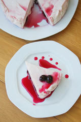 Cheesecake with sour cherries and sauce on a plate on wooden table. Sour cherry cheesecake on a plate