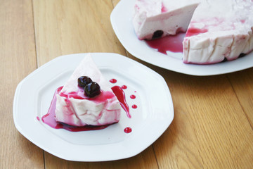 Cheesecake with sour cherries and sauce on a plate on wooden table. Sour cherry cheesecake on a plate