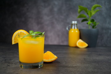 A glass of fresh orange juice on grey background.