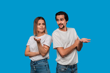 Couple of a young blond woman and brunet bearded man with mustaches in white t-shirts and blue...