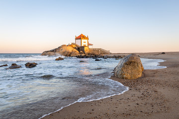 Sunrise at the beach with a church in the sea (Senhor da Pedra Chapel)