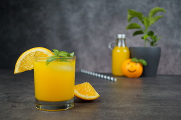 A glass of fresh orange juice on grey background.