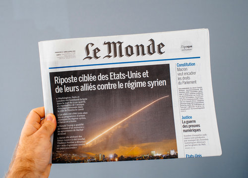 PARIS, FRANCE - APR 15, 2014: Le Monde French newspaper in man hand with cover showing Bombing Syria missle by Washington, London and Paris