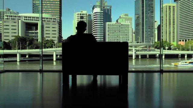 Person sits in chair with at river and city skyline