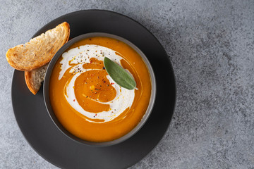 Pumpkin soup with sage on grey background. Top view.