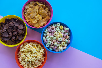 Corn flakes in bowl with spoon on colorful background