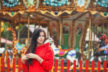 Fototapeta na wymiar Young beautiful brunette woman happy in the Park on the background of bright colored carousel