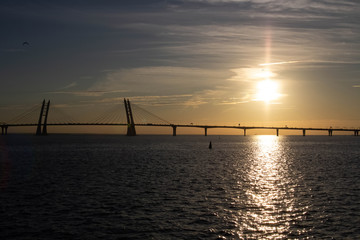 Fototapeta na wymiar Long cable-stayed bridge on the background of a beautiful sunset on the sea