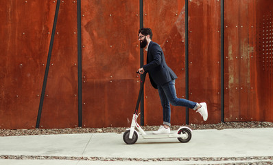 Cheerful hipster riding electric scooter
