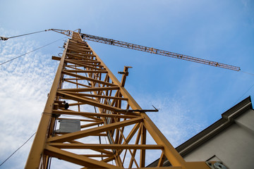 Construction site with cranes on sky background. Big yellow machinery construction crane tool of building industry for heavy lifting on blue sky background. Business engineering equipment modern