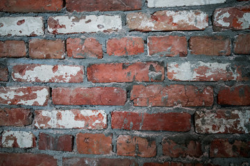 Naklejka premium The wall of red dilapidated brick. The ruined brick wall close-up. Facade of a destroyed brick building. Pattern, texture, background.