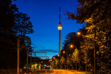Germany, Empty street alongside railway leading to famous television tower of stuttgart city, called fernsehturm by night in magical twilight atmosphere