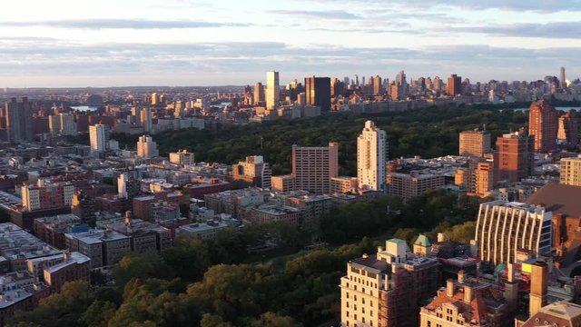 Aerial footage pans from the Upper West Side across to Harlem neighborhoods of NYC.  Gorgeous sunrise golden hour colors across the urban rooftops.  in 4K.