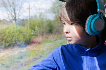 the girl looks out the window of the train and listening to music in headphones.