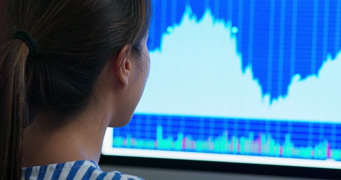Woman look at the stock market data on computer monitor