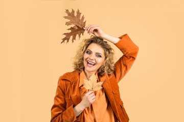 Autumn time. Woman holds yellow leaf. Woman with yellow leaves. Smiling woman with autumn leaves. Season sale. Discount. Sale. Autumn mood. Autumn fashion model. Fashion trends for fall. Leaf fall.