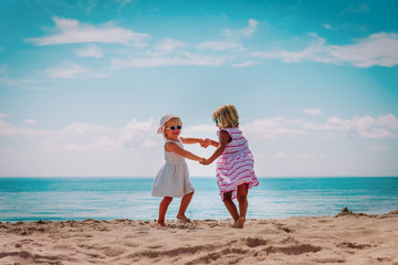 cute little girls dance play at summer beach