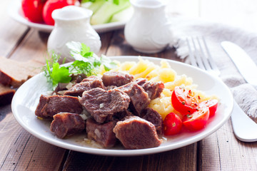 Beef stew with mashed potatoes on a white plate on a wooden table, horizontal