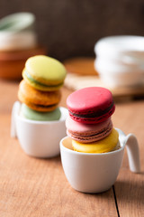 Pile of sweet and colourful french macaroons on wood background.