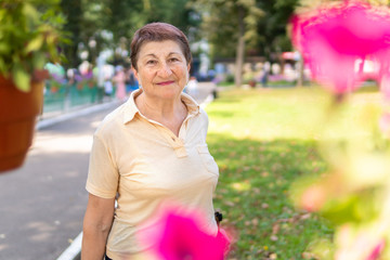Old woman walks nordic with sticks in the Park on a Sunny summer day outdoors
