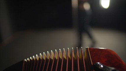 Close-up musician playing the accordion against a black background. playing the button accordion in the studio