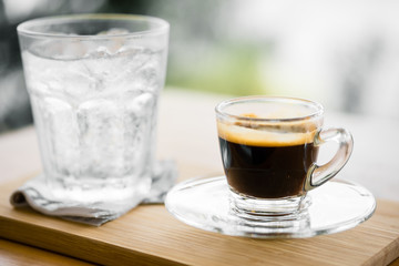 close up hot coffee in glass.barista make hot espresso shot from professional coffee machine.hot espresso shot on bottom plate at coffee shop with daylight background in the morning.