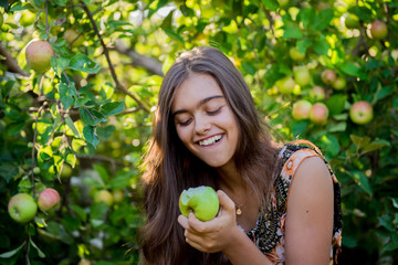 Girl in the apple orchard eating an apple. Autumn fruit picking. Young girl with long hair. Balanced Nutrition, Vegetarianism