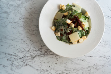 Cesar salad with bacon cheese on white plate in luxury restaurant.