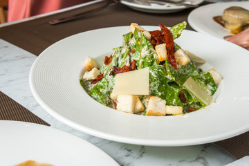 Cesar salad with bacon cheese on white plate in luxury restaurant.