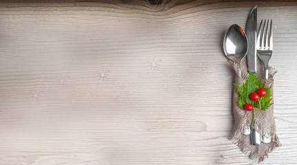 Thanksgiving autumn place setting with cutlery and arrangement of green leaf, red berries