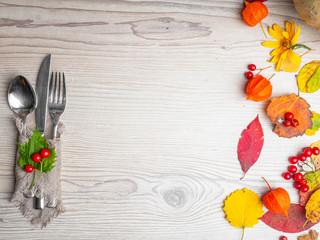 festive Thanksgiving autumn place setting with cutlery and arrangement of colorful leaf, red berries
