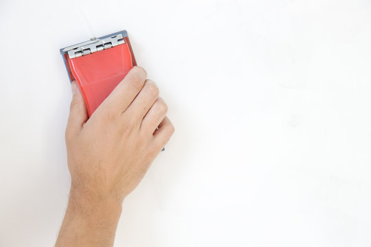 Process of sanding wall with a sanding block after skim coating. Preparation before painting. Renovation house concept.