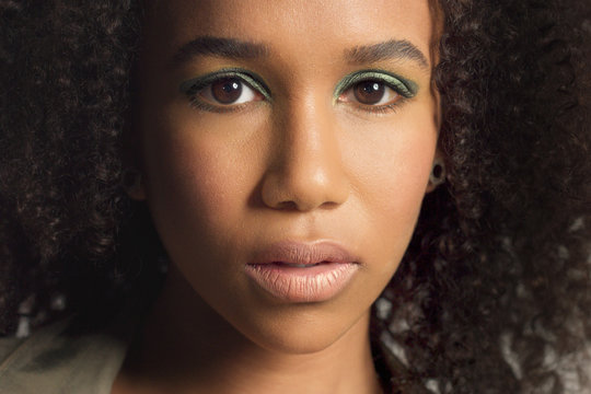 closeup portrait of young mixed race model with curly hair. Face closeup with briight green makeup