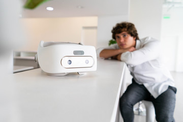 Obraz premium Man sitting near virtual reality goggles in modern contemporary bright co-working office. the VR experience.