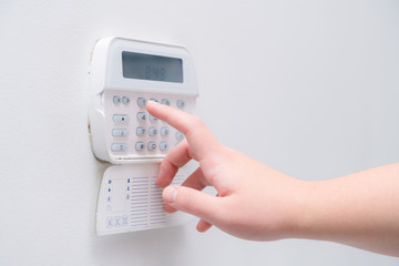 Woman hand entering alarm system password of an apartment, house of business office. Surveillance and protection console against rubbery and thief