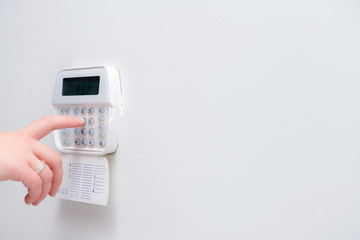 Woman hand entering alarm system password of an apartment, house of business office. Surveillance and protection console against rubbery and thief