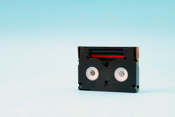 Vintage mini DV cassette tape used for recording video back in a day. Plastic, magnetic, analog film tape on blue background