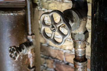 Rusty valves on boiler room pipes. Old metal boiler generating heating and delivering it to home through pipeline