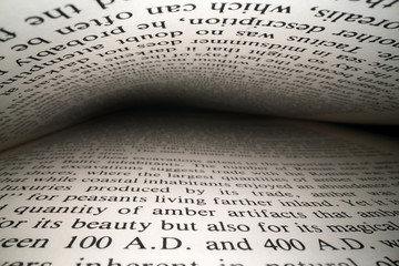 Inside the book concept. Latin letters and words on an open book with black dramatic background. Education, knowledge concept