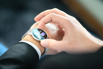 Fototapeta premium Smart watch with touch screen. Business man using wearable device with mobile technology. Smartwatch with finance report or banking app. Person wearing digital gadget in hand. Hybrid wearables concept