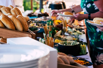 Close up view of people firends hands taking food from catering table during party celebration -...