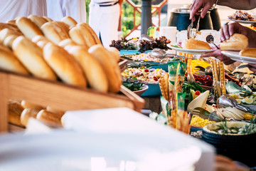 Close up view of people firends hands taking food from catering table during party celebration - food on a table -coloured background and together