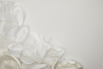 top view of crumpled plastic cups and plates white background with copy space