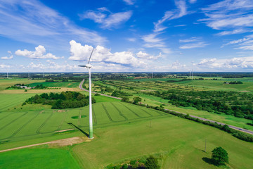 Wind turbines in open green field with blue sky background. 