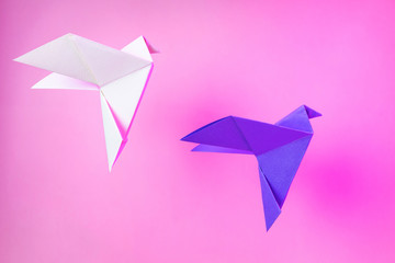 Origami paper two doves on a pastel pink background. Violet and white dove. The concept of arts and...