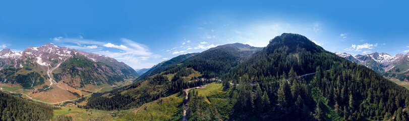 Fototapeta na wymiar Aerial view Grossglockner Hochalpenstrasse, Alpine Road in Austria. Pine forest, sunny summer day, blue sky. Motorcyclists and travelers road. vacation and adventure, hiking and active lifestyle